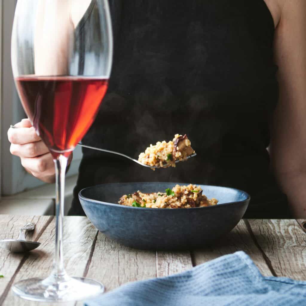 bicchiere di vino rosato con donna che mangia riso